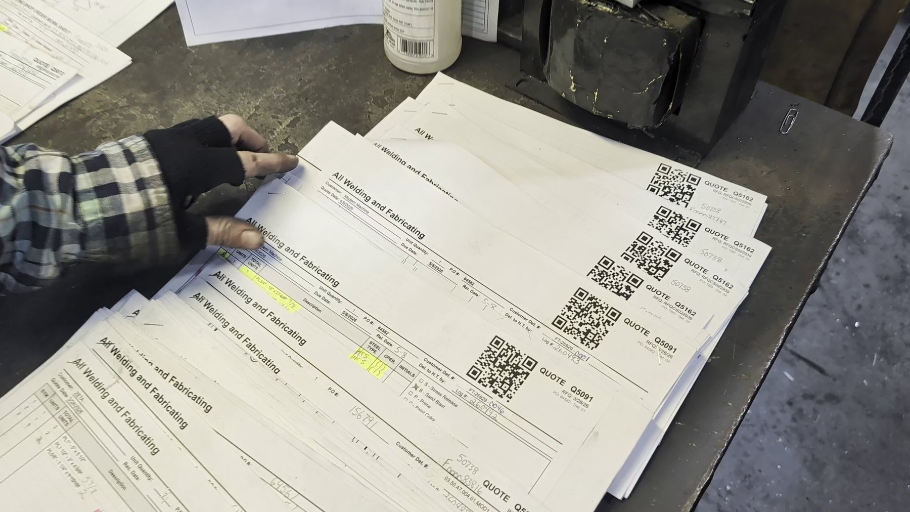 Stack of printed shop travelers with QR codes ready for the floor